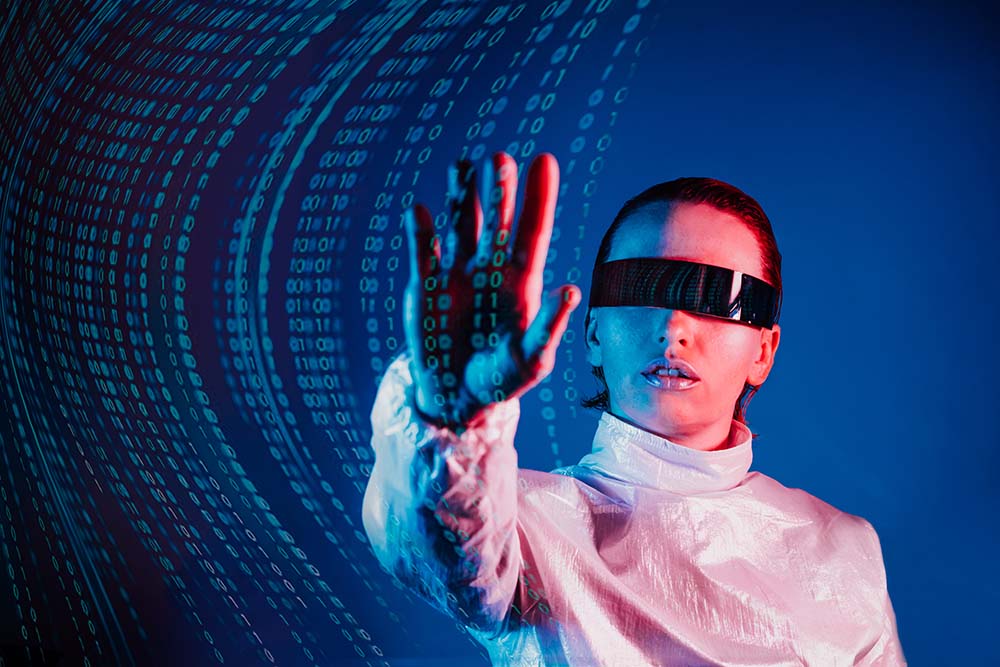 Woman dressed in holographic clothes and futuristic eyeglasses with reflection of matrix code is touching by hand matrix digital numbers artificial intelligence data before her in blue light